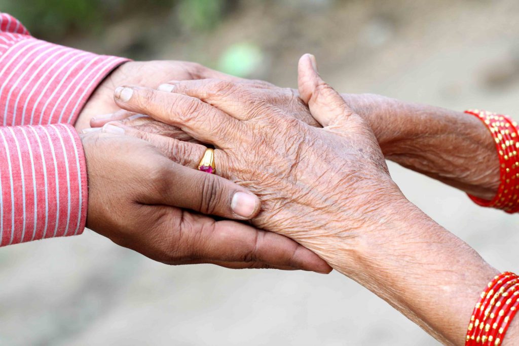 Older person holding hands with a younger person
