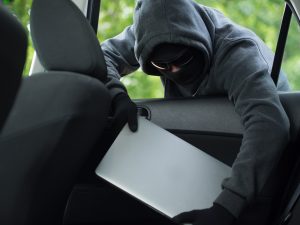 Thief stealing a laptop through a car window