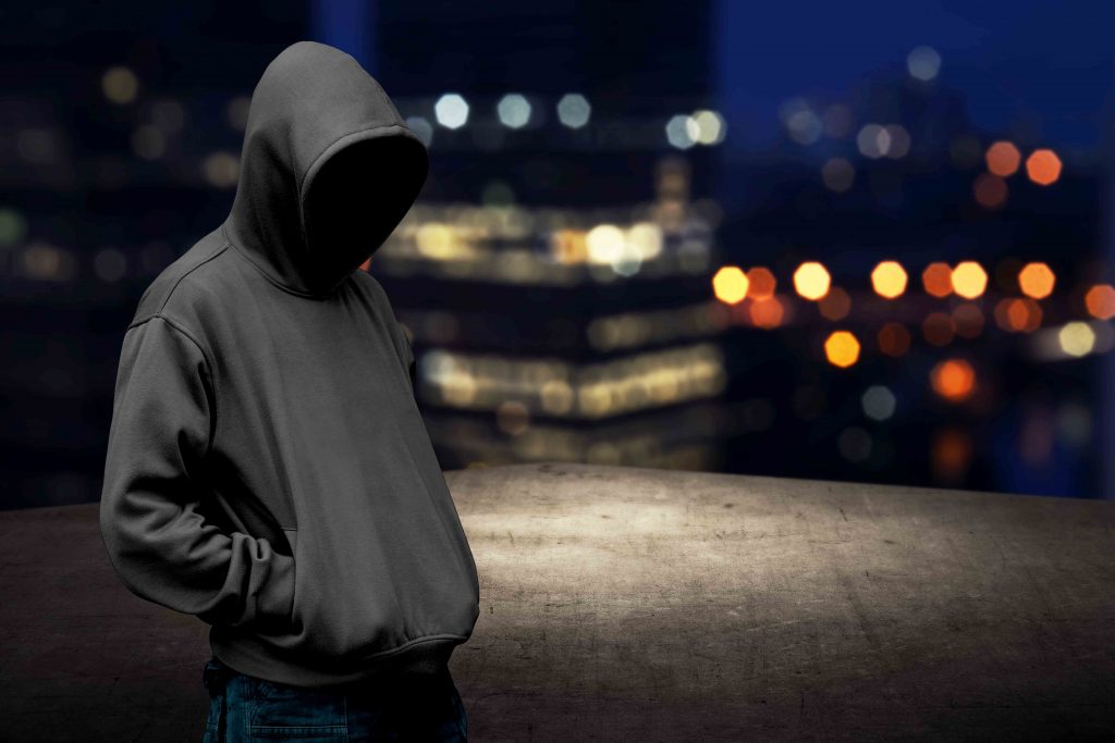 A person in a hoodie late at night with darkness shielding their face